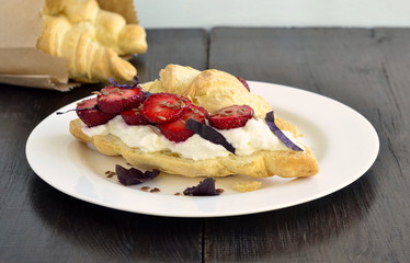 Croissant with cream cheese, strawberries and basil for breakfast
