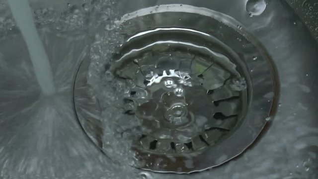 Kitchen sink, water flows from the tap into the hole in the sink.