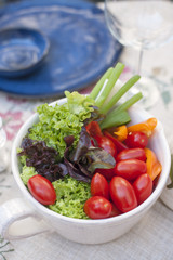 Fresh vegetable salad in a cup on the dining table. Ingredients for summer salad. Vitamins and benefits. Copy space.