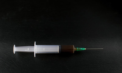 A syringe with a drug on a dark background.
