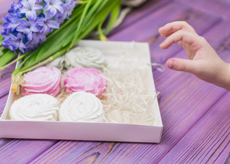 The child's hand reaches out for a candy box with a marshmallow (zephyr).