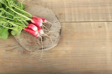 heap of fresh red radish with green leaves  isolated on wooden background