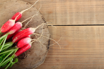 heap of fresh red radish with green leaves  isolated on wooden background