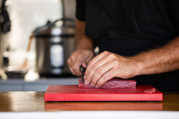 Fototapeta na wymiar Crop chef slicing fresh tuna