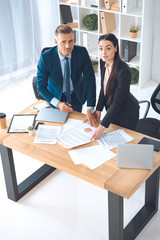high angle view of business colleagues doing paperwork at workplace in office