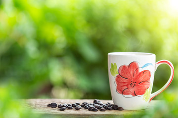 Coffee cup on wooden table or counter with green nature light blur background and space for text, design, photo montage or advertising