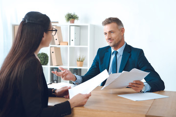 business partners with papers discussing work at workplace in office
