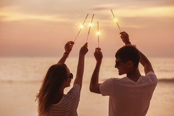 Happy couple celebrates sunset with sparklers