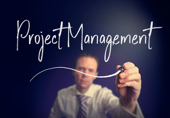 A businessman writing a Project Management concept with a white pen on a clear screen.