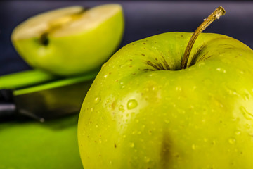 Green fresh apples, chopped up on the old board. On a wooden table.