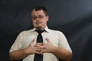 Punk stands with glasses. White shirt, dark tie. Facial expression is serious and good-natured....