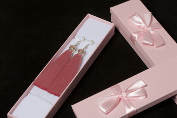 Earrings made of viscose handmade. Together with wrapping gift boxes. Against the black background.