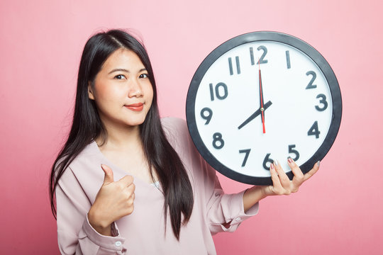 Young Asian woman thumbs up with a clock.