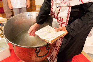 Orthodox priest blesses the water. Baptism ceremony.