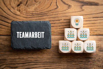 Schiefertafel mit Wort "Teamarbeit" und Würfel mit Team-Symbolen