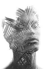 Double exposure of a young sexy man’s portrait blended with branches of a tropical palm tree,...
