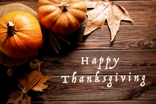 Happy thanksgiving concept. Still life composition with pumpkin and oher fruits and vegetble small decoration with funny font text white text. Wood textured table background. Top view, close up.