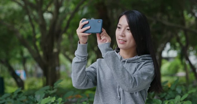 Woman take photo on cellphone in park