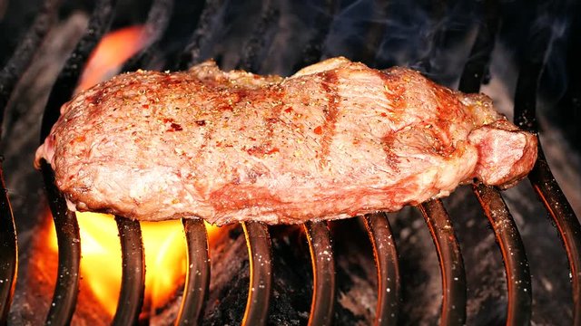 Delicious beef steak on a barbecue grill in slow motion