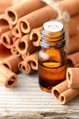 cinnamon oil and cinnamon sticks on the wooden board