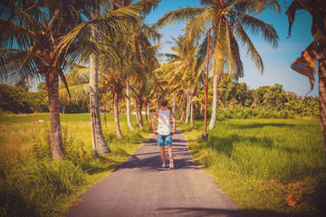 Man walking in tropical paradise in the middle of a road.