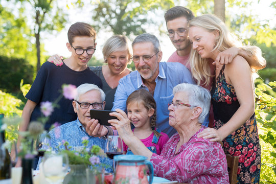 During a bbq, the family have fun sharing a video on a phone