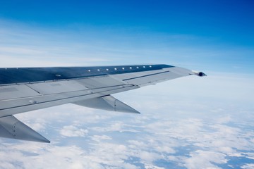 Obraz premium Airplane Wing Out of Window with Clouds and Sky