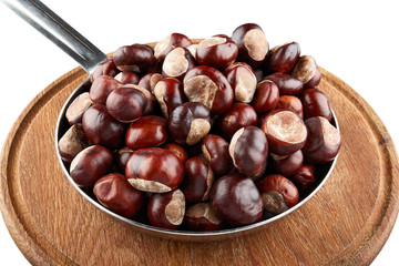 Many chestnuts in frying pan on wooden plate