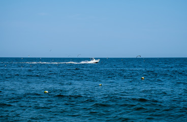 Boat racing across open ocean water. Boat speeding in the sea. Minimal nature photography. Beach view of maritime transportation. Minimal abstract nature landscape photography. 
