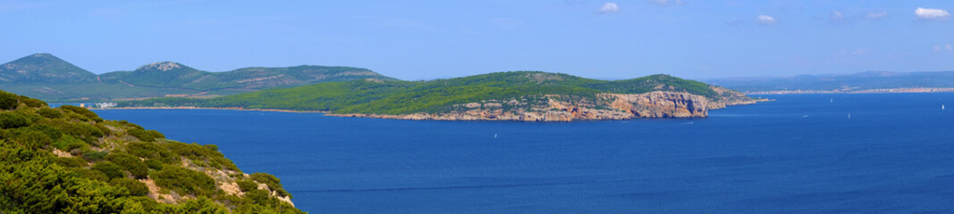 Fototapeta na wymiar Alghero, Italy - Panoramic view of the Gulf of Alghero with cliffs of Punta del Giglio and city of Alghero in background