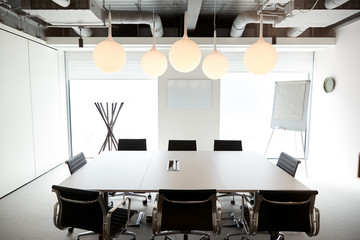 Chairs Around Boardroom Table In Empty Modern Meeting Room