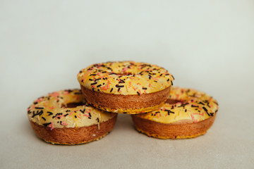 Three yellow donuts biscuits on gray background, beautiful sweet food