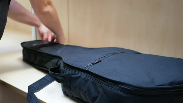 Guitar player pulls an acoustic guitar out of a black case and checks it