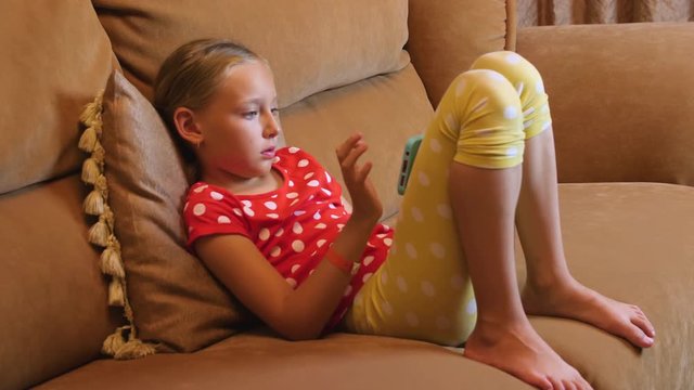 Teenager girl sitting on couch using mobile phone in living room interior