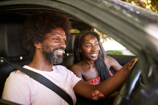 Two young black adults sitting in a car during road trip