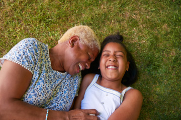 Black girl and grandmother lying on grass, overhead close up - obrazy, fototapety, plakaty