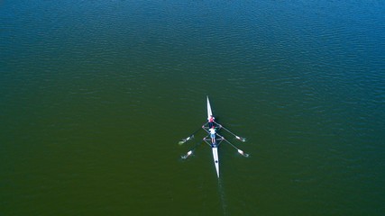 Boat coxed four rowers rowing on the tranquil lake. Aerial view of rowing and rowers.