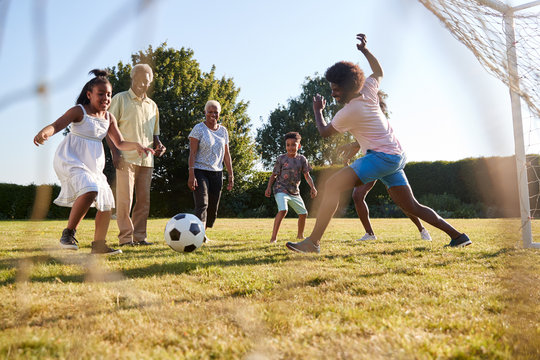 Multi generation black family playing football in a garden