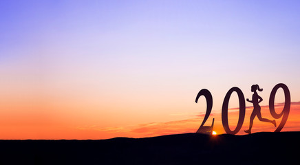 2019 On dark mountains with silhouette of a woman running and sunrise as background.