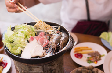 Asian girl is grilling pork in Korean style.