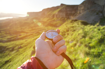 Man searching direction with a compass in his hand in the summer mountains point of view. Direction Search