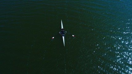 Boat coxed four rowers rowing on the tranquil lake. Aerial view of rowing and rowers.