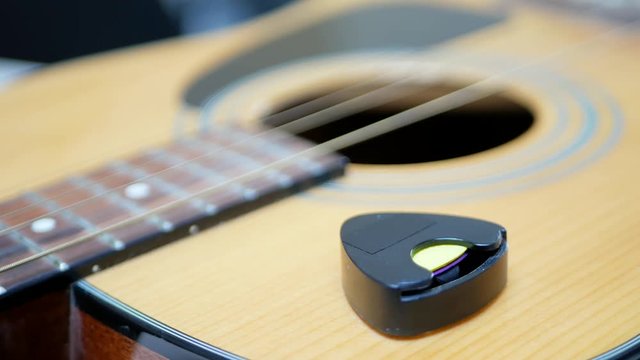 Guitarist takes a mediator or plectrum from an acoustic guitar