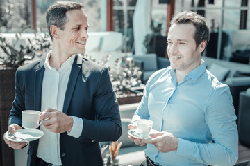 Time to relax. Attractive male person expressing positivity and turning head while having pleasant conversation