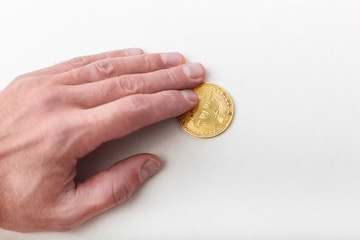 A man hand holds bitcoin on an isolated background. Close up man holds in hand bitcoin, metal coin of golden color isolated on white background.  Copy space.