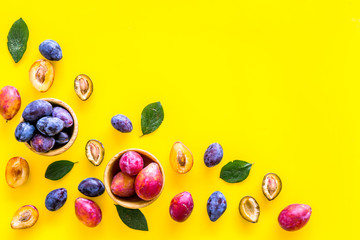 Bright fruitty background. Plum pattern. Red and purple plum and leaves on yellow background top view copy space