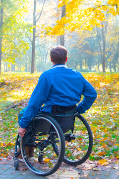 person with a disability, lonely man in wheelchair looking at the autumn park