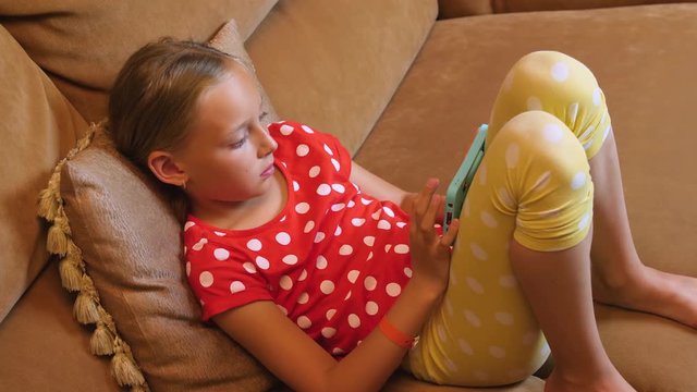 Young girl sitting on couch and browsing mobile phone in cozy living room