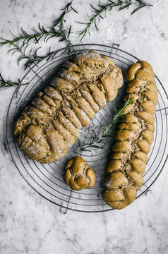 Overhead view of rosemary, garlic, and olive oil plaited rye bread on cooling rack