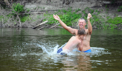 Father throws his son in the water, play, fun family vacation. jumps, swims and splashes in the river.